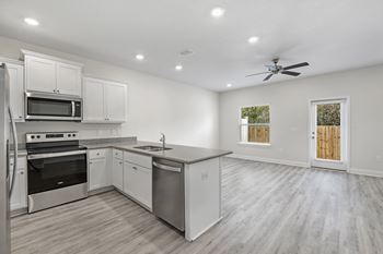 a kitchen and living room with white walls and a ceiling fan